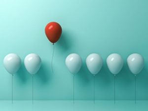 いくつかの白い風船と赤い1つの風船