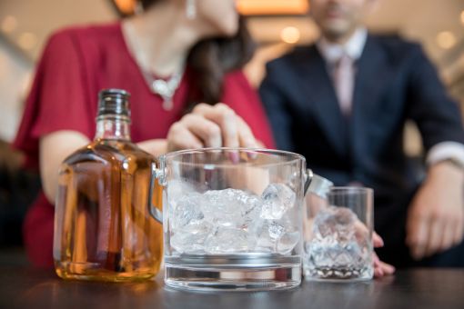 ウイスキーを作るドレスの女性とスーツの男性